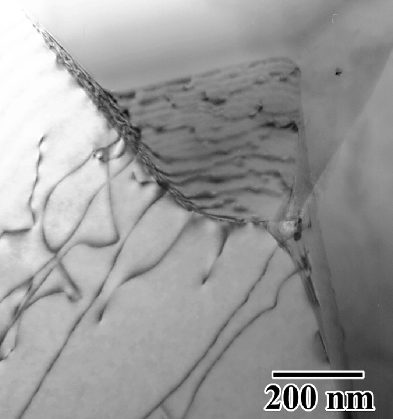A transmission electron micrograph of a grain boundary junction and associated defects following superplastic forming.