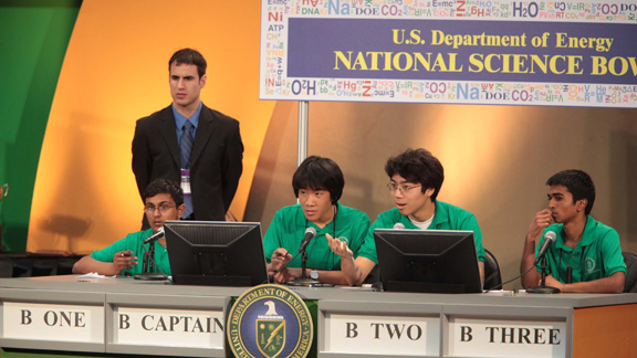 Four High School boys sitting at a table during a competing  facing the camera